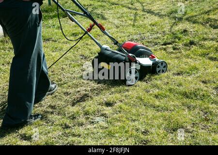 Aération avec scarificateur. Utiliser un scarificateur dans le jardin pour améliorer la qualité de la pelouse au printemps. Un travailleur, Gardener, qui fait fonctionner l'aération du sol Banque D'Images