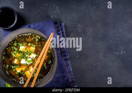 Soupe miso au bol en potelé, avec algues wakame, tofu et baguettes sur fond noir Banque D'Images