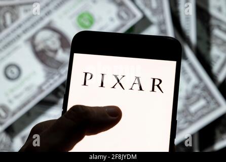 Dans cette illustration de photo, le studio américain de film d'animation d'ordinateur appartenant à Disney, le logo Pixar est vu sur un écran d'appareil mobile Android avec la devise de l'icône dollar des États-Unis, symbole d'icône $ en arrière-plan. Banque D'Images