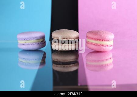 Trois macarons sur un fond bleu noir rose différentes couleurs différents goûts avec place pour le texte et la réflexion. Banque D'Images
