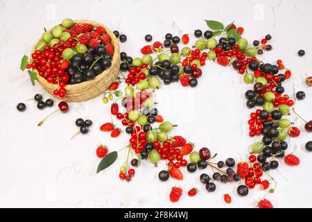 Les groseilles d'été, les framboises et les groseilles à maquereau sont en forme de coeur sur fond blanc. Bordure de baies. Vue rapprochée du dessus ou plan de travail à plat avec pla Banque D'Images