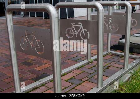 Boulonné à la structure de la chaussée d'arcs verticaux en métal en rangée avec plaques avec coupe de l'image de vélo pour le stationnement sortie et fixation de vélos avec pavés Banque D'Images