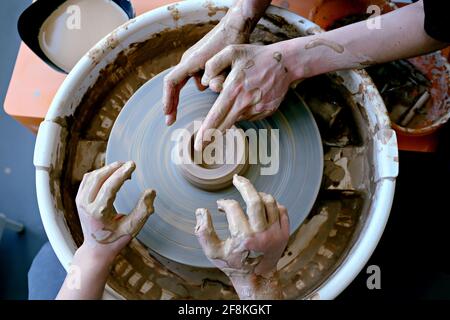 De belles mains de femmes et d'adolescents au-dessus de la roue de potier. Sculptez de l'argile dans un atelier de poterie. Poterie traditionnelle. Atelier de céramique conce Banque D'Images