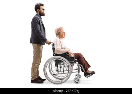 Prise de vue sur toute la longueur d'un homme barbu poussant un femme âgée assise dans un fauteuil roulant isolé sur fond blanc Banque D'Images