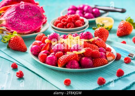 Salade de fruits frais de dragon avec fraises, framboises et fruits de départ (carambola) sur fond cyan Banque D'Images