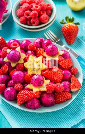 Salade de fruits frais de dragon avec fraises, framboises et fruits de départ (carambola) sur fond cyan Banque D'Images