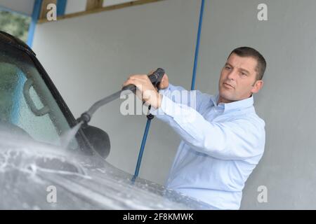 homme lavant une voiture avec de l'eau sous pression Banque D'Images