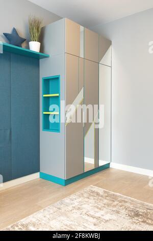Une armoire grise avec des étagères à créneaux, avec un motif géométrique sur la façade, avec des miroirs, dans la chambre d'un adolescent. Concept de détails intérieurs modernes dans Banque D'Images