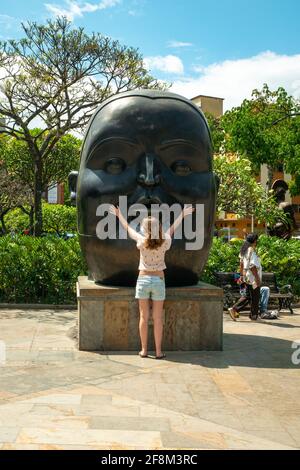 Medellin, Antioquia, Colombie - janvier 6 2021: Fille caucasienne posant devant une sculpture de bronze, une statue d'une tête de graisse par Fernando Botero à Pla Banque D'Images