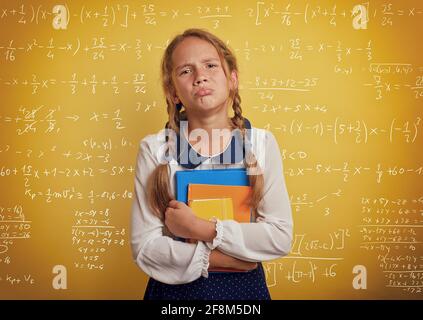 Fille pleure parce qu'il a beaucoup de devoirs à l'école. Expression émotionnelle. Arrière-plan jaune Banque D'Images