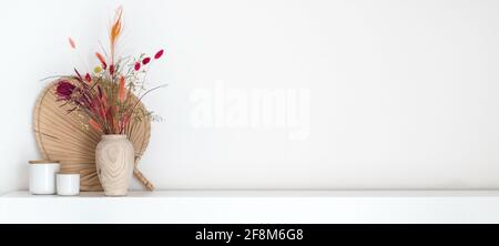 En-tête de bouquet de fleurs séchées colorées dans un style boho vase en bois debout sur une étagère blanche avec beaucoup de copier l'espace Banque D'Images