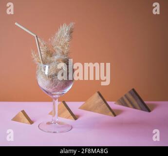 Cocktail de pampas dans un verre avec une paille en tige de pampas. Arrière-plan minimal de composition abstraite. Idée d'intérieur Japandi. Une idée de rafraîchissement. Banque D'Images