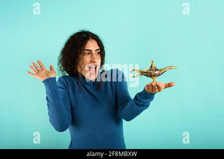 La femme est heureuse de voir qu'elle fonde la lampe d'aladdin. Fond cyan Banque D'Images