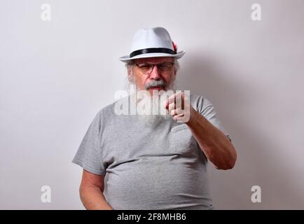 Vieux homme portant fedora blanc donnant un look sceptique et pointant vers la caméra Banque D'Images