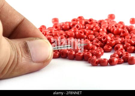 Gros plan de la main d'une femme clouant des perles sur une aiguille perles avec macro aiguille, utilisé dans la finition des vêtements de mode faire collier de perles Banque D'Images