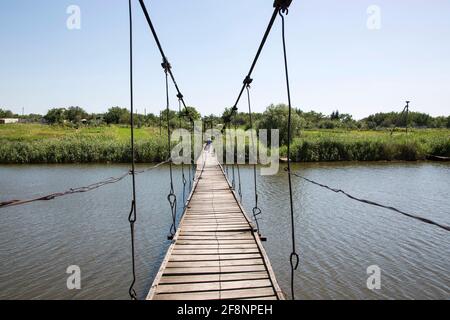Un homme marche sur un pont suspendu au-dessus de la rivière Banque D'Images