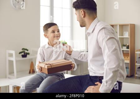 Père millénaire aimant et adorable petit fils avec cadeau emballé à la maison Banque D'Images