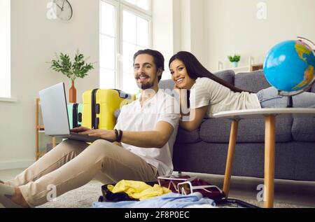 Un jeune couple planifie un voyage de vacances et utilise un ordinateur portable pour acheter billets ou réserver une chambre d'hôtel Banque D'Images