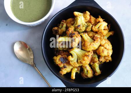 Gobi ou Gobhi Tandoori. Le chou-fleur rôti au masala est un plat indien végétarien populaire servi avec du chutney à la menthe et à la coriandre. Banque D'Images