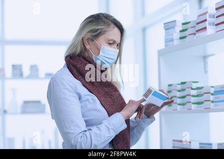 La pharmacie d'accueil de femme choisit la médecine dans le masque de protection Banque D'Images