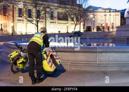 Un ambulancier de Londres vérifie son mobile Pour la prochaine affectation à côté de la fontaine à la place Trafalgar Banque D'Images