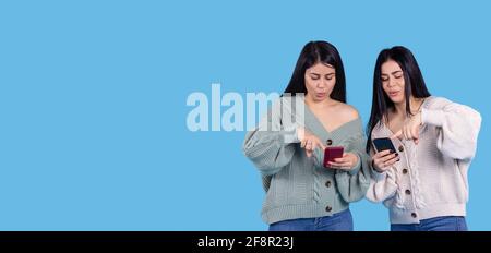 Bannière. Sœurs jumelles stupéfait, stupéfait, effrayée, effrayé. Les filles regardent le smartphone entre leurs mains, pointant avec l'index vers l'écran Banque D'Images