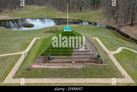 15 avril 2021, Brandebourg, Branitz: Les employés du Parc du Musée Fürst-Pückler et de la Fondation du Château Branitz travaillent sur les pas de la pyramide terrestre historique dans le Parc Branitz à Cottbus (photographie aérienne prise avec un drone). La pyramide terrestre du parc Branitz retient actuellement ses marches historiques de la terre des quatre côtés. Grâce à ce travail difficile, les jardiniers du parc créent une contribution cadeau très spéciale pour le 175e anniversaire du paysage du parc Branitz de cette année à partir de leurs propres ressources. Fin avril 2021, les travaux consistent en la modélisation de la terre et la pose de gazon en rouleau Banque D'Images