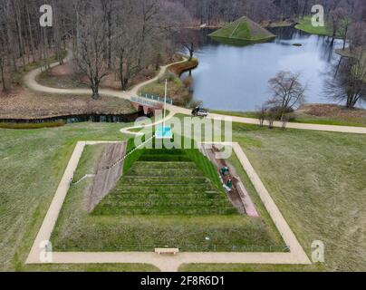 15 avril 2021, Brandebourg, Branitz: Employés du Parc du Musée Fürst-Pückler et de la Fondation du Château Branitz travaillant sur les pas de la pyramide terrestre historique dans le Parc Branitz à Cottbus (photographie aérienne prise avec un drone). La pyramide du lac peut être vue en arrière-plan. La pyramide terrestre du parc Branitz conserve actuellement ses marches historiques de la terre des quatre côtés. Grâce à ce travail difficile, les jardiniers du parc créent une contribution cadeau très spéciale pour le 175e anniversaire du paysage du parc Branitz de la part des forces de la fondation. Fin avril 2021, le travail Banque D'Images