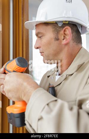 craftsman entraîne la vis dans le cadre en bois Banque D'Images