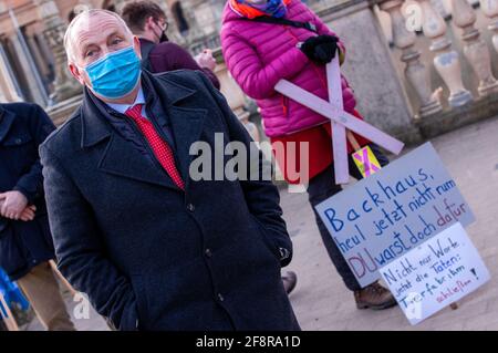 15 avril 2021, Mecklembourg-Poméranie occidentale, Schwerin: Till Backhaus (SPD, l), ministre de l'Agriculture de Mecklembourg-Poméranie occidentale, se dresse devant une bannière lisant 'Backhaus, ne pleurez pas maintenant rhum.' lors d'une manifestation par des activistes animaux et environnementaux. La fin des « usines d'animaux » est demandée devant le bâtiment du Parlement de l'État dans le château de Schwerin à la suite de l'incendie d'une ferme de porcs à Alt Telellin. Il faut mettre fin à l'élevage industriel et prendre davantage en considération le bien-être des animaux. Dans le feu dévastateur de la ferme porceuse Alt Tellin, environ 55,000 truies et porcelets sont morts à agon Banque D'Images