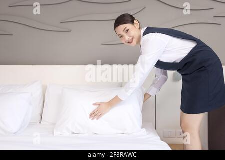 Vue en grand angle d'une serveuse qui fait le lit, la femme de ménage qui nettoie une chambre d'hôtel Banque D'Images