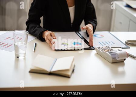 Femme d'affaires assise à son bureau travaillant sur le rapport financier avec des graphiques et des graphiques. Banque D'Images