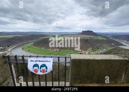 14 avril 2021, Saxe, Königstein: Un avis "les masques sont obligatoires ici" est suspendu sur la rambarde de la forteresse de Königstein en Suisse saxonne, avec l'Elbe et le Lilienstein en arrière-plan. Les portes de la forteresse historique sont ouvertes aux visiteurs depuis le 12 avril après plus de cinq mois de fermeture due à la couronne. Photo: Robert Michael/dpa-Zentralbild/ZB Banque D'Images