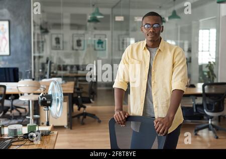 Un jeune homme d'affaires africain penchait sur une chaise dans un moderne bureau Banque D'Images