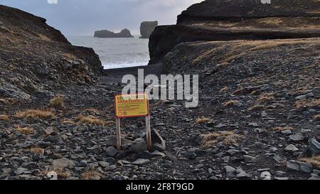 Panneau d'avertissement de couleur jaune (zone fermée) à l'entrée de Kirkjufjara sur la côte atlantique sur la péninsule de Dyrhólaey dans le sud de l'Islande avec des rochers. Banque D'Images