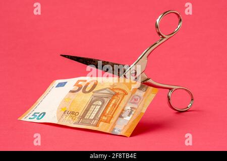 Couper cinquante euros avec des ciseaux sur fond rose. Concept sur le thème de la dévaluation de l'argent. Banque D'Images