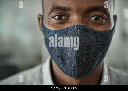 Homme d'affaires africain portant un masque de protection dans son bureau Banque D'Images