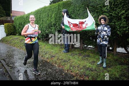 Swansea, pays de Galles, 4 octobre 2020. Météo au Royaume-Uni : les supporters avec un drapeau gallois brave la forte pluie à Swansea, au sud du pays de Galles pour venir et encourager un coureur prenant part au Marathon virtuel de Londres. Crédit photo : Robert Melen. Banque D'Images