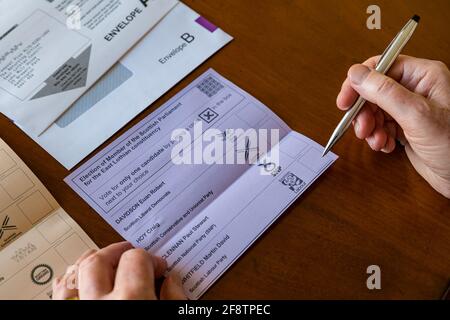 East Lothian, Écosse, Royaume-Uni, 15 avril 2021. Les bulletins postaux arrivent pour les élections écossaises : les résidents du comté peuvent voter pour la MSP du Lothian est et la région du sud de l'Écosse. Les candidats pour les premiers sont Euan Davidson (Démocrates libéraux écossais), Craig Hoy (conservateurs écossais et unionistes), Paul McLennan (SNP) et Martin Whitfield (Parti travailliste écossais et ancien député qui a perdu en 2019 à Kenny MacAskill, qui est en lice pour Alba). La liste régionale comprend 16 parties. Un homme choisit pour qui voter sur le bulletin de vote Banque D'Images