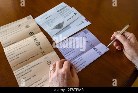 East Lothian, Écosse, Royaume-Uni, 15 avril 2021. Les bulletins postaux arrivent pour les élections écossaises : les résidents du comté peuvent voter pour la MSP du Lothian est et la région du sud de l'Écosse. Les candidats pour les premiers sont Euan Davidson (Démocrates libéraux écossais), Craig Hoy (conservateurs écossais et unionistes), Paul McLennan (SNP) et Martin Whitfield (Parti travailliste écossais et ancien député qui a perdu en 2019 à Kenny MacAskill, qui est en lice pour Alba). La liste régionale comprend 16 parties. Un homme choisit pour qui voter sur le bulletin de vote Banque D'Images