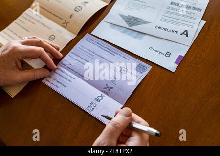 East Lothian, Écosse, Royaume-Uni, 15 avril 2021. Les bulletins postaux arrivent pour les élections écossaises : les résidents du comté peuvent voter pour la MSP du Lothian est et la région du sud de l'Écosse. Les candidats pour les premiers sont Euan Davidson (Démocrates libéraux écossais), Craig Hoy (conservateurs écossais et unionistes), Paul McLennan (SNP) et Martin Whitfield (Parti travailliste écossais et ancien député qui a perdu en 2019 à Kenny MacAskill, qui est en lice pour Alba). La liste régionale comprend 16 parties. Un homme choisit pour qui voter sur le bulletin de vote Banque D'Images