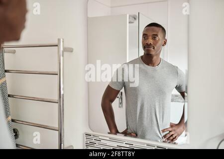 Jeune Africain debout dans sa salle de bain le matin Banque D'Images