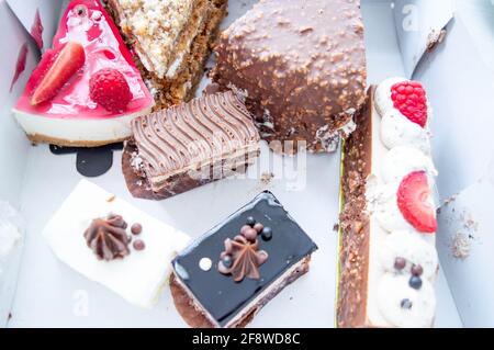 Morceaux de gâteaux et pâtisseries dans une boîte du magasin. Vue de dessus. Une boîte de gâteaux au chocolat, aux fruits et aux framboises Banque D'Images