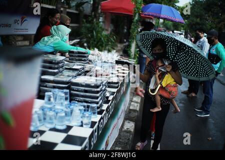 Jakarta, DKI Jakarta, Indonésie. 15 avril 2021. Les résidents font la queue en appliquant la règle de distance teh pour obtenir le takjil gratuit sur les routes du centre de Jakarta, jeudi (04/15/2021). Les résidents sont tenus de faire la queue en appliquant une distance de deux mètres pour prévenir la propagation du coronavirus. EEveryday le comité fournit gratuitement 400-600 paquets takjil qui sont des dons de résidents et des entreprises de la région. Crédit : Muhammad Zaenuddin/ZUMA Wire/Alay Live News Banque D'Images