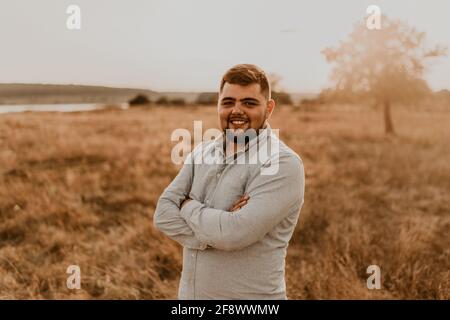 jeune caucasien noir-cheveux surpoids homme avec la barbe sourire gaiement en coton d'été vêtements et shorts en plein air par temps ensoleillé. hommes mode co Banque D'Images