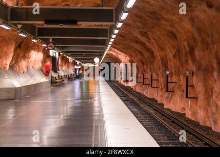 Stockholm, Suède juin 7 2019 : métro souterrain station de métro tunnelbana Radhuset avec escalier roulant et grottes à motifs brun orange murs et plafond Banque D'Images