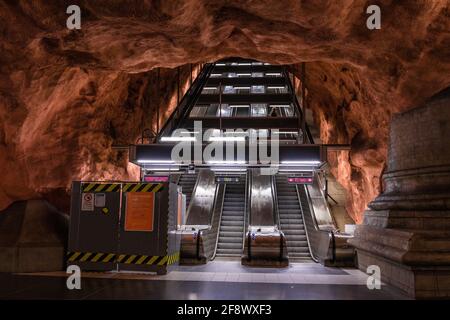 Stockholm, Suède juin 7 2019 : métro souterrain station de métro tunnelbana Radhuset avec escalier roulant et grottes à motifs brun orange murs et plafond Banque D'Images