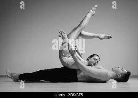 Posture du cirque intense. Un jeune homme tient une femme flexible. Deux acrobates ou danseurs de ballet se posant sur un fond blanc. Une paire de gymnastes exécutent l'art. Banque D'Images