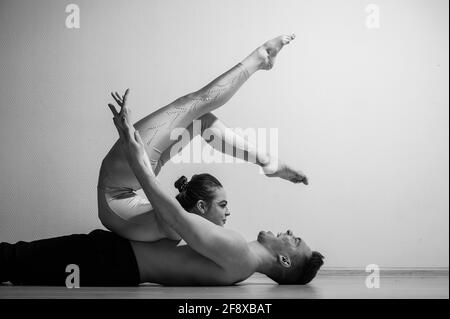 Posture du cirque intense. Un jeune homme tient une femme flexible. Deux acrobates ou danseurs de ballet se posant sur un fond blanc. Une paire de gymnastes exécutent l'art. Banque D'Images