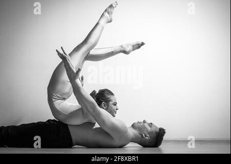 Posture du cirque intense. Un jeune homme tient une femme flexible. Deux acrobates ou danseurs de ballet se posant sur un fond blanc. Une paire de gymnastes exécutent l'art. Banque D'Images